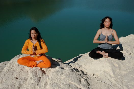 MOther and daughter, yoga at beautiful lakeside setting