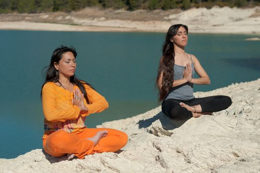 MOther and daughter, yoga at beautiful lakeside setting