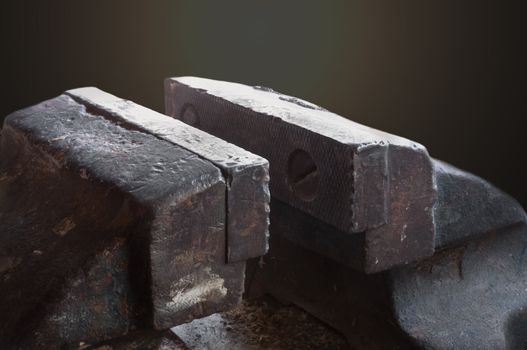 Close up on part of a very old metal vice with dark background