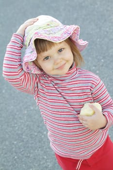 Cute little girl with an apple outdoors