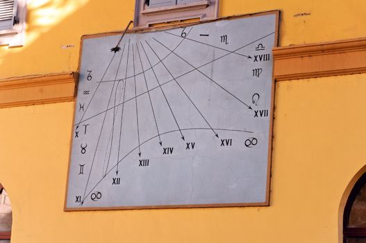 An Italian sundial on a wall with roman numarals and zodiac signs
