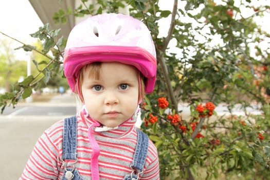 Cute little girl with pink bicycle helmet outdoors
