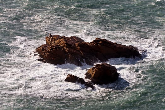 The brown rock in a stormy ocean