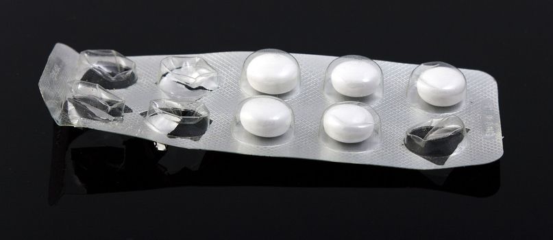 used packaging of pills and reflecting, black background