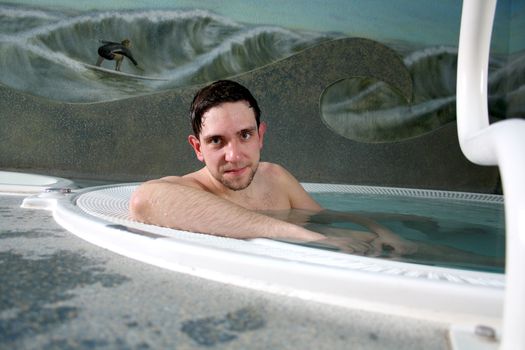 A pretty boy is lying relaxed in the pool 