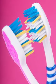 A couple of toothbrushes over pink background