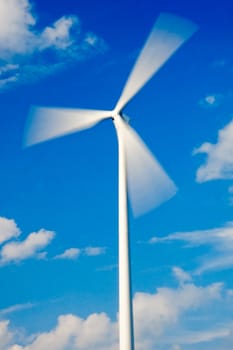 Fast spinning wind turbine and blue sky with few clouds (rotor with strong motion blur)