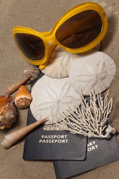 Close-Up of passports, sun glasses, sand dollars (Echinoderm), coral and shells: Beach Vacation Concept