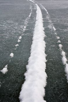 Snowmobile tracks on ice surface of frozen lake