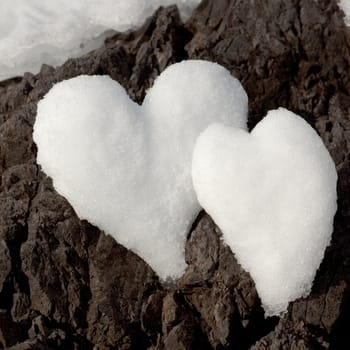 Two Valentine�s Day Hearts formed from snow on rock surface.