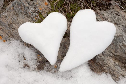 Two Valentine�s Day Hearts formed from snow on rock surface.