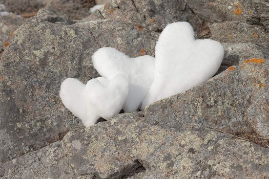 Thtree Valentine�s Day Hearts formed from snow on rock surface.