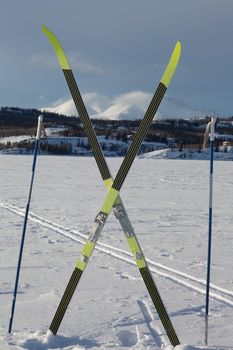 Cross country skiing. Skis and poles near ski track on frozen lake. Perfect winter snow conditions with blue sky.