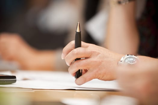 Human hand holding a pencil on a table