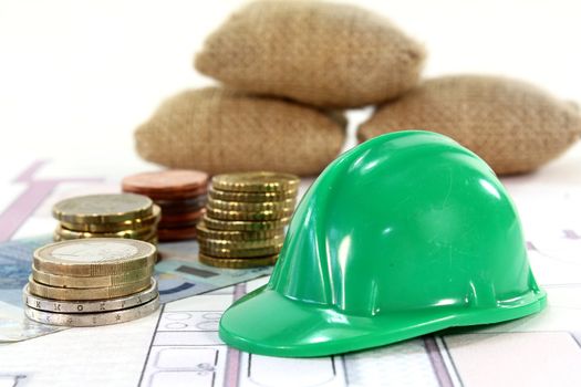 Construction helmet with euros on a housing plan