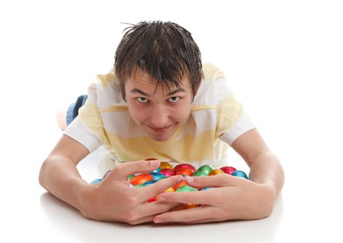 A greedy or lucky boy hoarding lots of chocolate easter eggs.  White background.