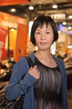 Modern Asian beauty in city night, half length closeup portrait on dark and illuminated urban background.