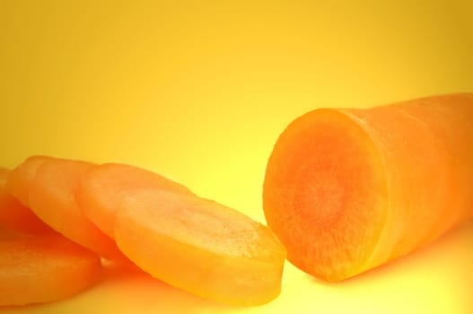 Close up on a partially sliced fresh organic carrot with vibrant yellow light effect background
