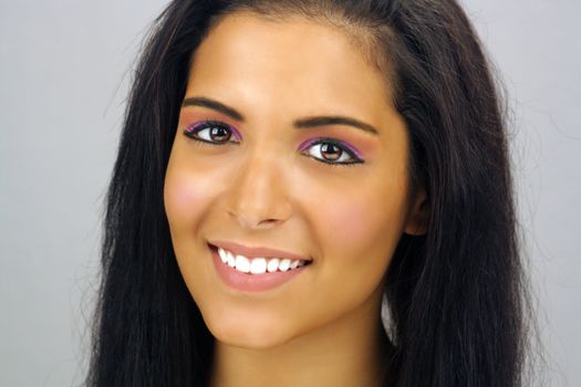 Close-up of a lovely teenage Latina with a bright, warm smile and long, luscious black hair.