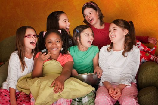 Group of little girls watching television while eating popcorn