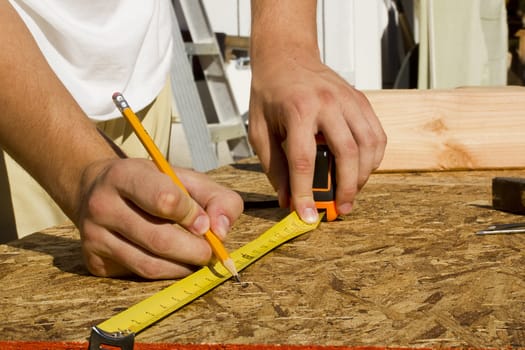 Closeup of a worker measuring a section of plywood.