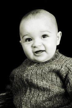 Baby boy against a dark background with a cute expression