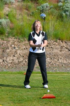 Blond female golfer on the tee-box with a driver