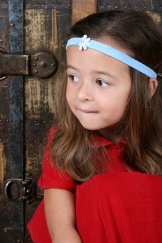 Cute brunette girl sitting against an antique trunk wearing a headband