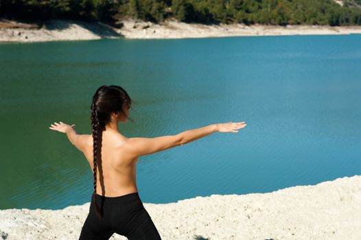 Woman enjoying early morning yoga on the shores of a lake