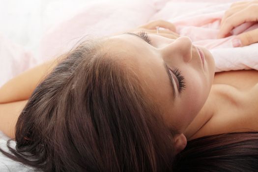 Sensual young woman laying in pink bed. Sleeping