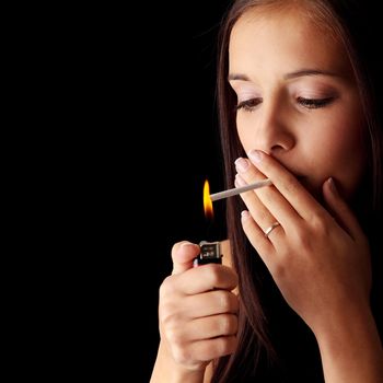 Young woman smoking over black background