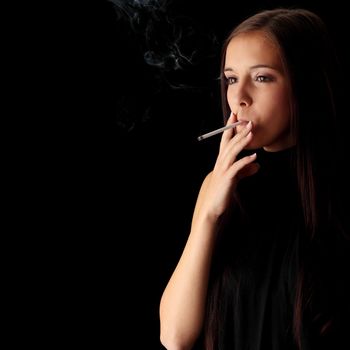 Young woman smoking over black background