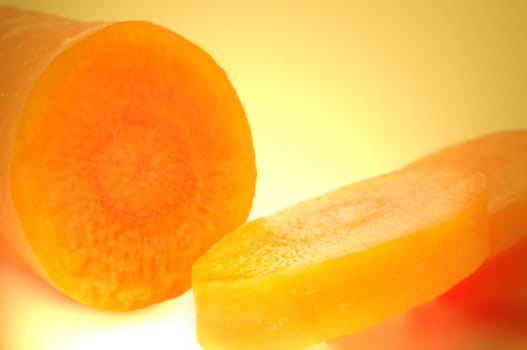 Macro shot of a portion of partially sliced fresh organic carrot with yellow light effect background
