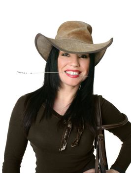 Smiling cowgirl wearing a leather western hat and carrying bridle.