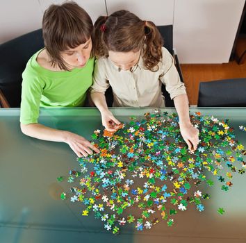 Teenager girl and her mother doing a puzzle at home