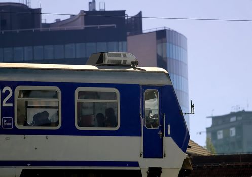 Photo of a public train passing trough the city in the morning with office building in the background
