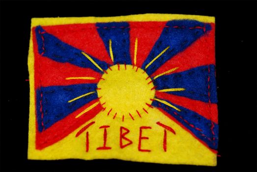 A Tibetan flag hand-sewn in felt on a black background