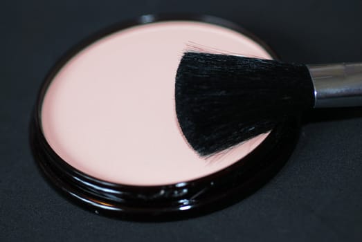 A close-up of cosmetics face powder or foundation with an applicator brush
