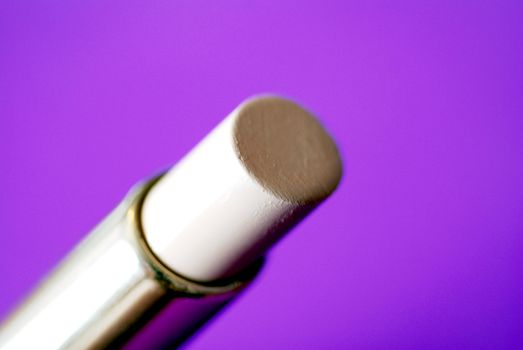 A tube of cosmetic concealer against a purple background
