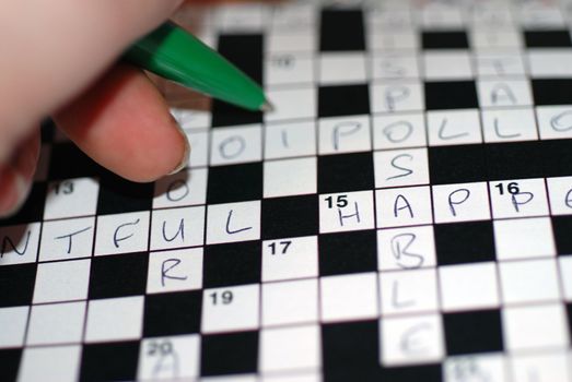 A close-up of a left-handed person filling in a crossword puzzles