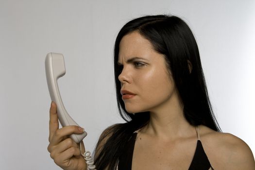 Woman looking puzzled at a phone receiver