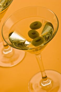 two bocal of martini with olive over yellow