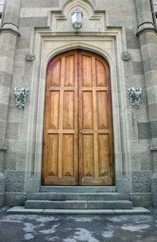 Wooden doors in ancient castle. On each side doors iron holders for torches and lantern. Ancient ornament on walls 