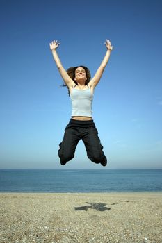 girl jumping on the beach withe blue sky