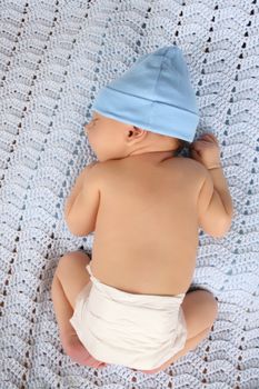 Beautiful baby boy wearing a blue hat on blanket