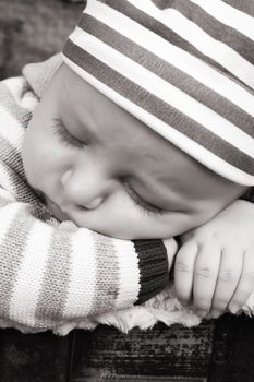 Beautiful baby boy sleeping in an antique trunk