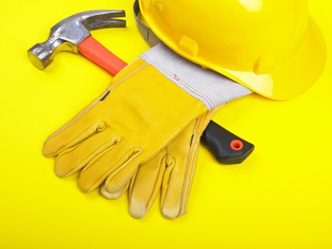 Worker equipment - HardHat Hammer And Leather Gloves on yellow