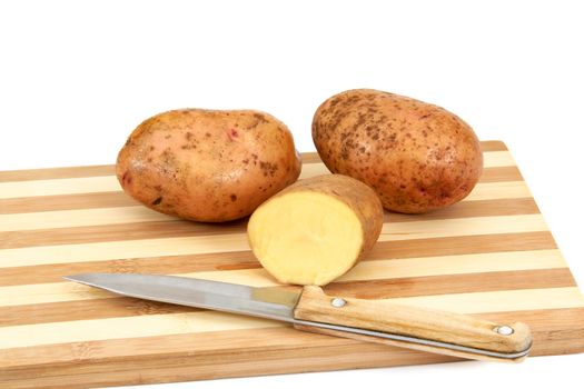 Raw potato tubers lying on a cutting board, isolated on a white background.