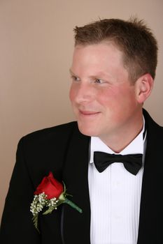 Smiling groom on his wedding day wearing a red rose corsage 