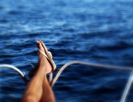 Boat travel conceptual photo - Legs on the prowl of the boat and the sea as background. Soft focus blur on the edges 
